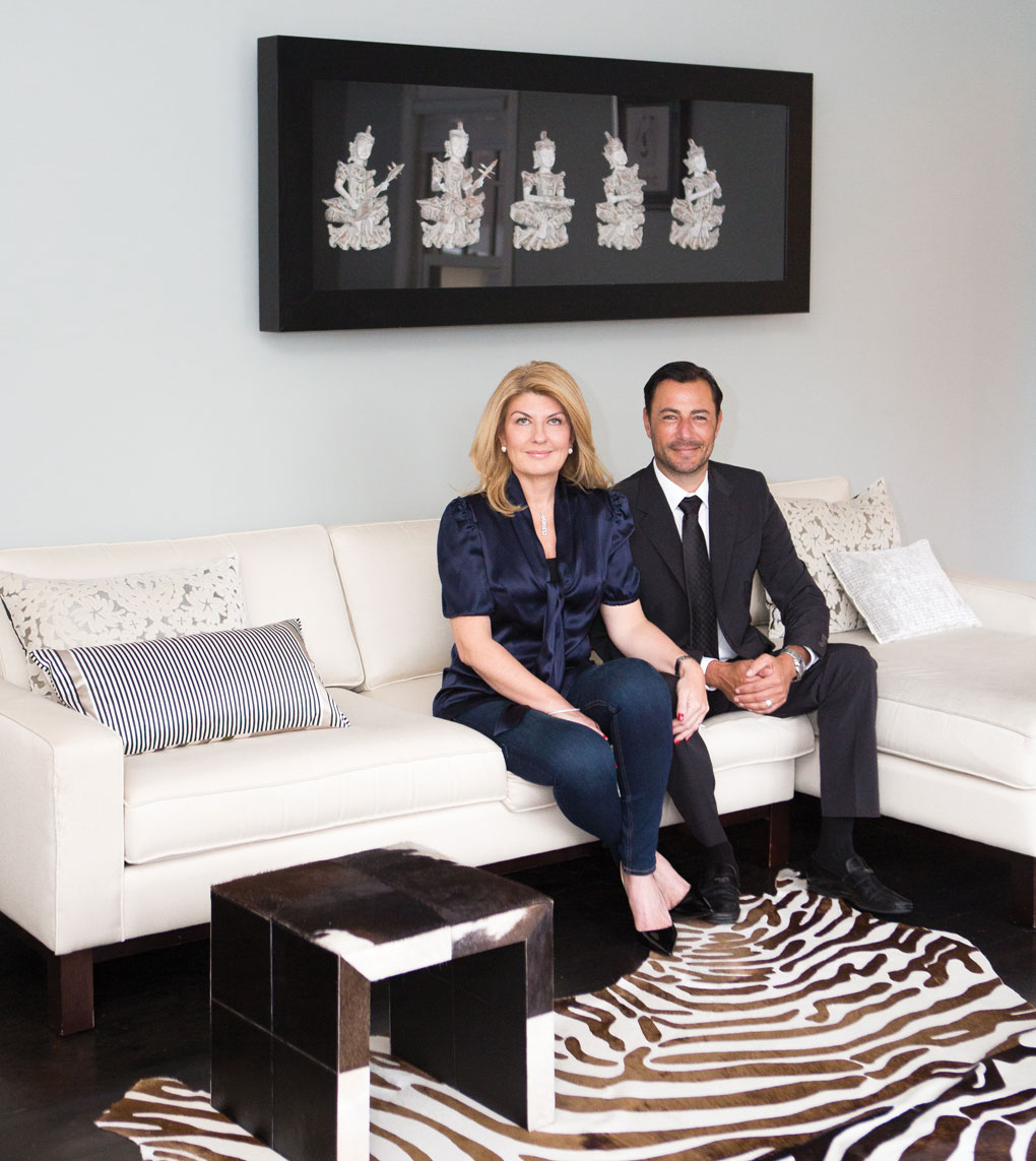 Daniel and Jane Green sit on a white sofa inside their home.