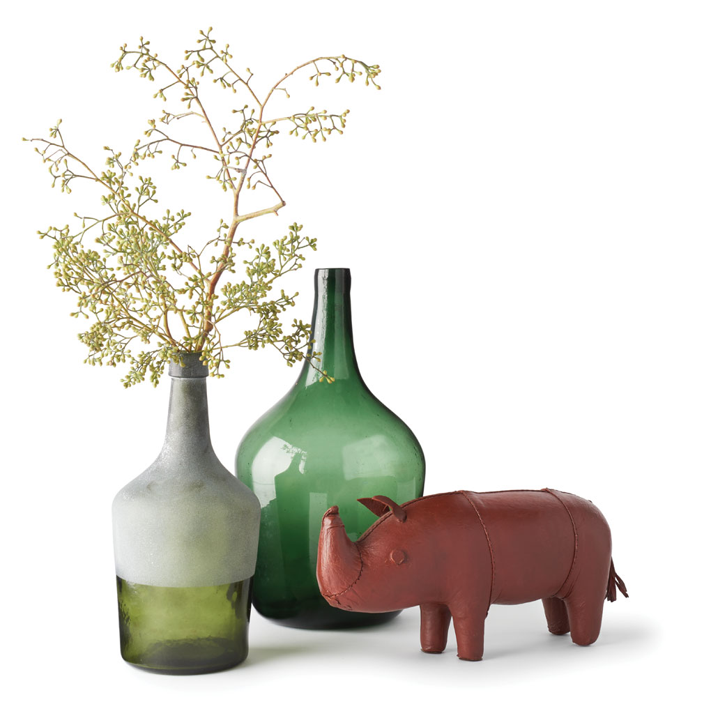 A Leather Smith rhino is set against two antique glass bottles.