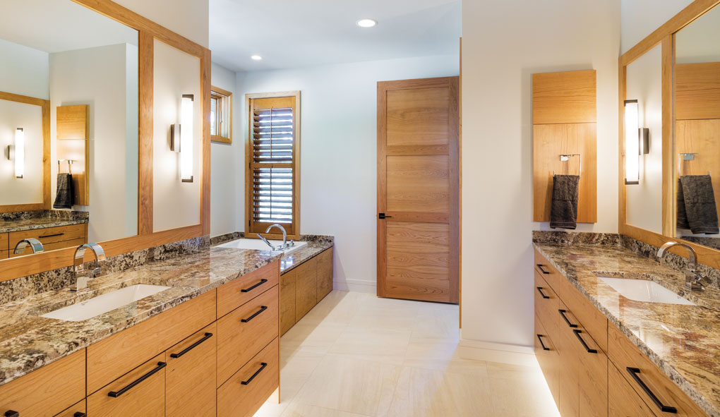 A master bath features twin vanities and sinks on each side of the room. A soaking tub lies beyond.