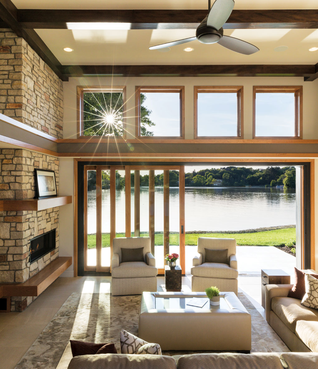A living room with a large glass door and windows opens up to a view of the river.