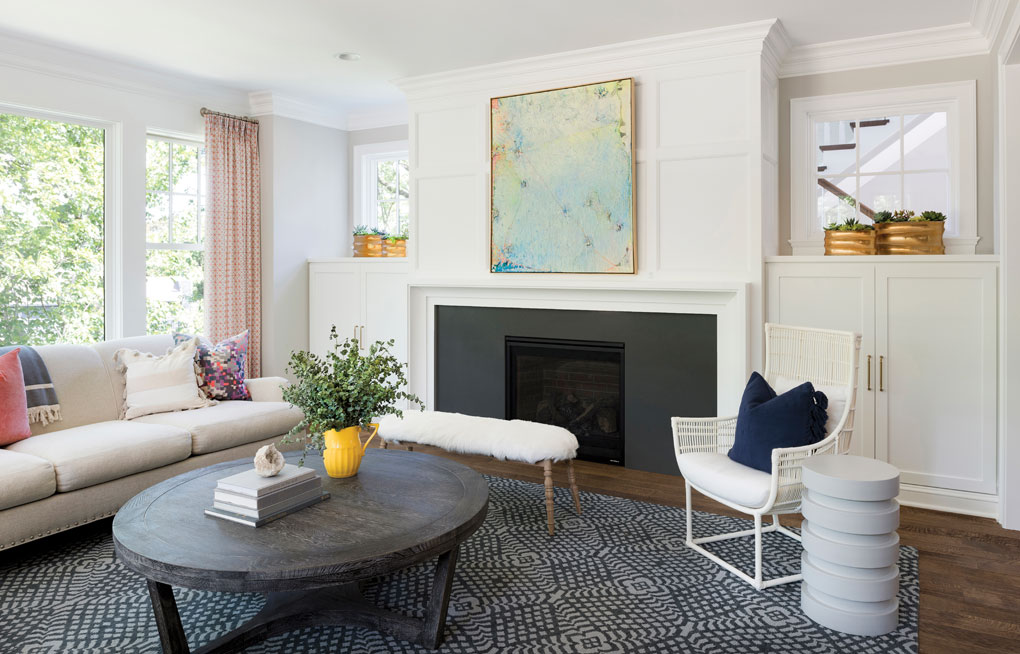 The cottage-style living room features fresh white paneling, millwork, and bookcases.