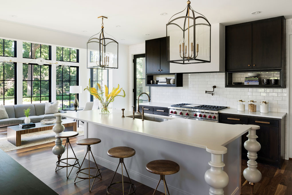 The open kitchen blends modern and traditional with a white subway tile backsplash, ebony-stained walnut cabinets, quartz-topped island, and stylized turned-wood legs.