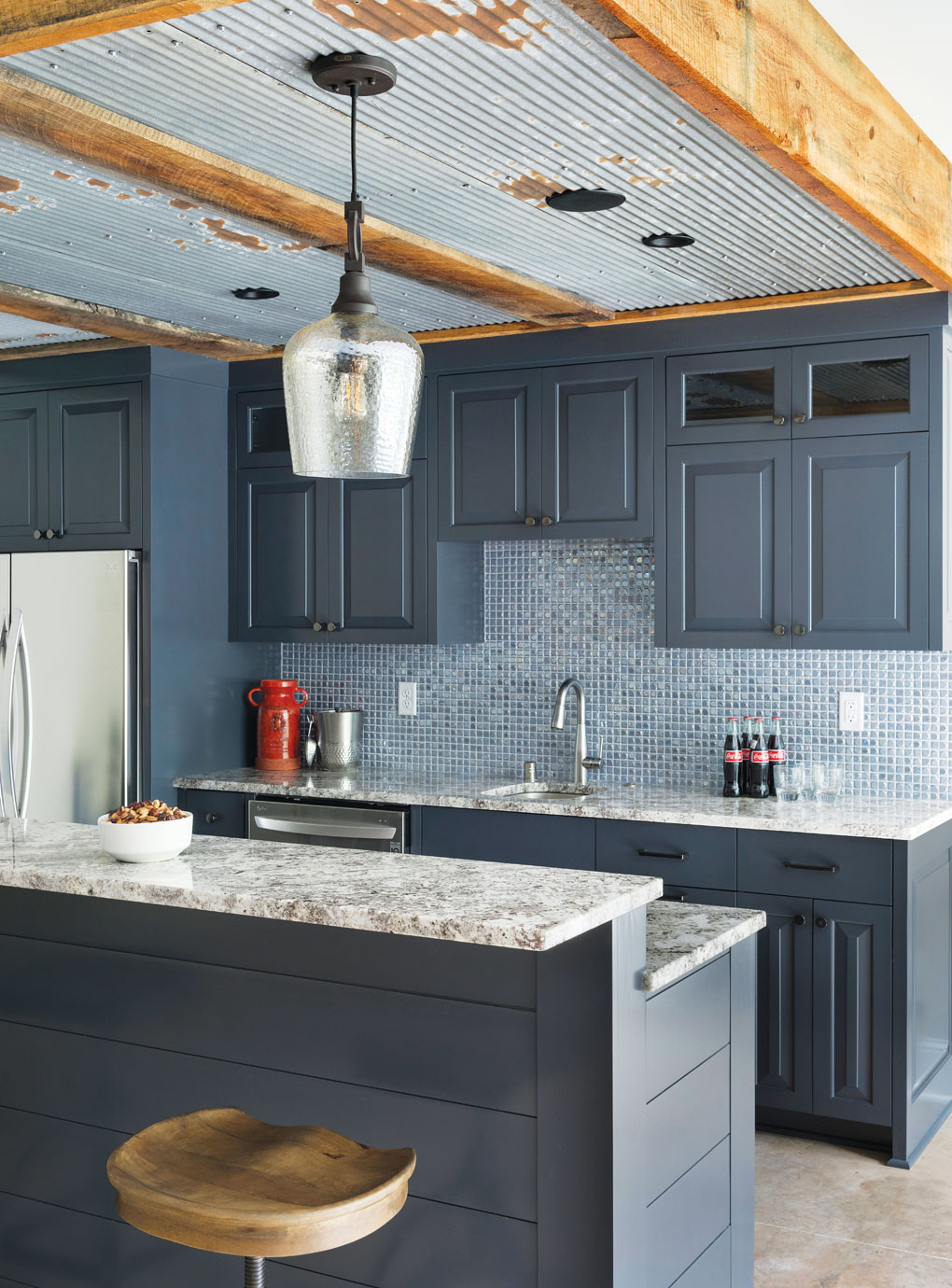 A bar in the lower level of a home features a tin ceiling and a custom bar topped with granite.