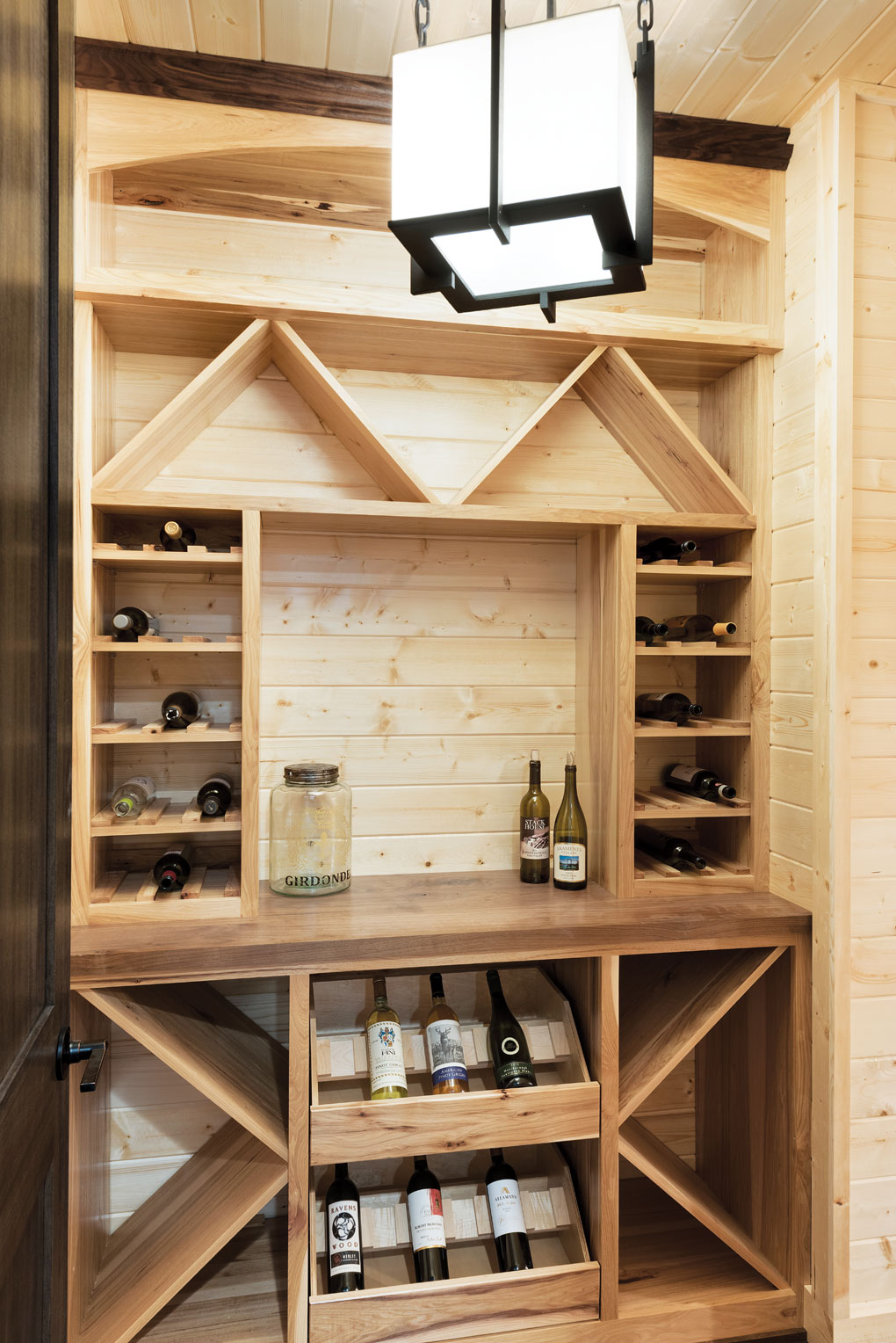 A knotty pine- and hickory-lined wine cellar stocked with bottles of wine.