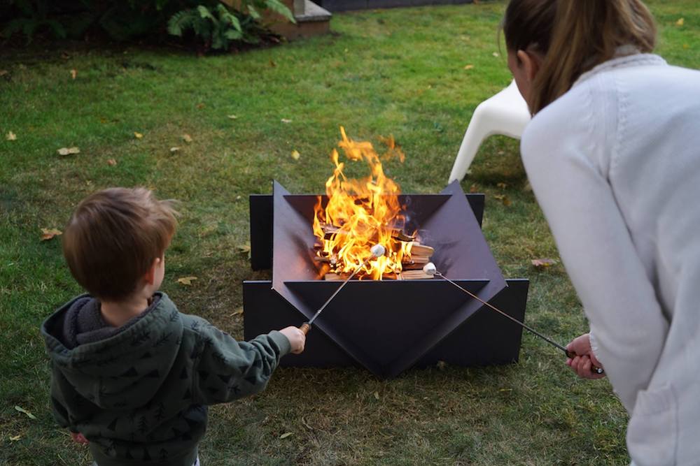A geometric fire pit with a family roasting marshmallows.