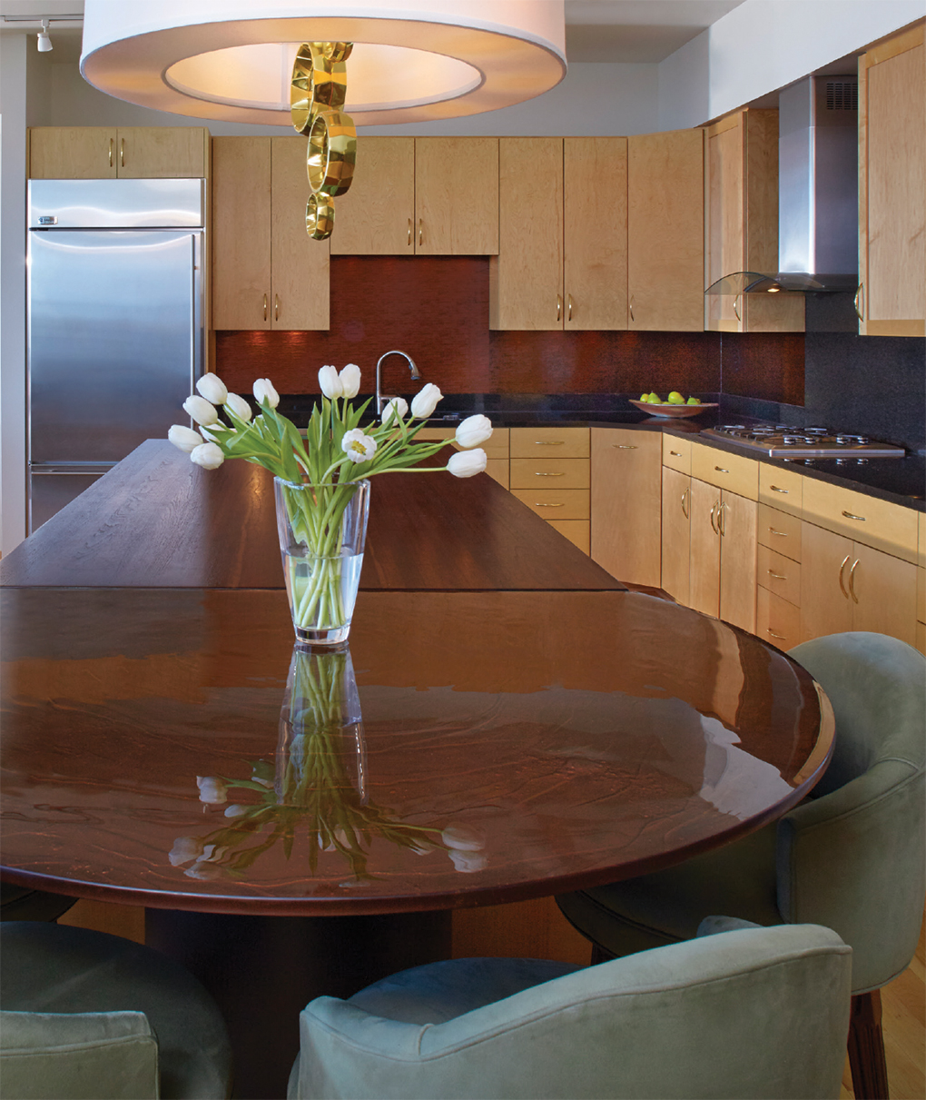 Kitchen and dining with dark wood tables and light wood cabinet space with stainless steel fridge