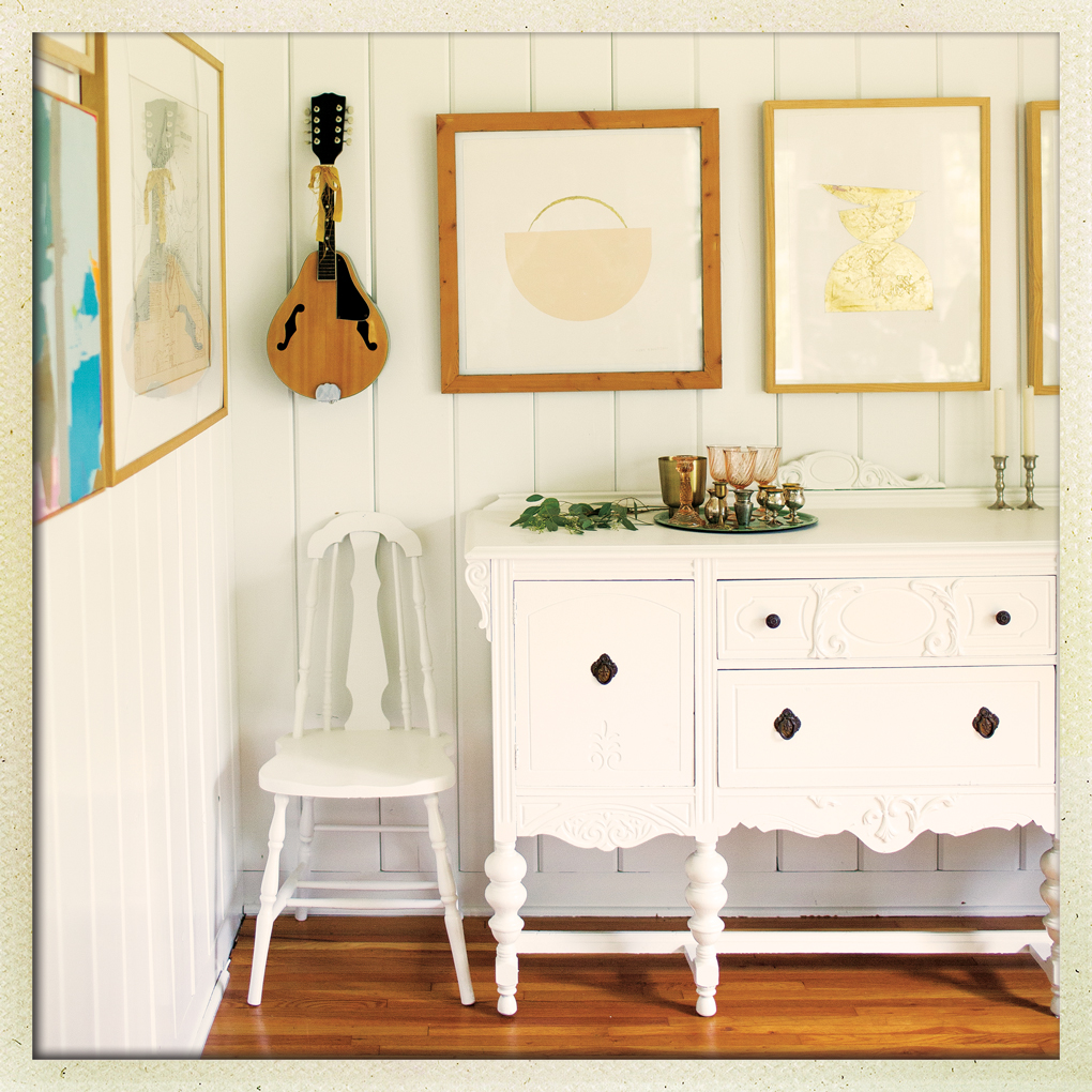 White kitchen with two frames and a mandolin mounted on the wall.