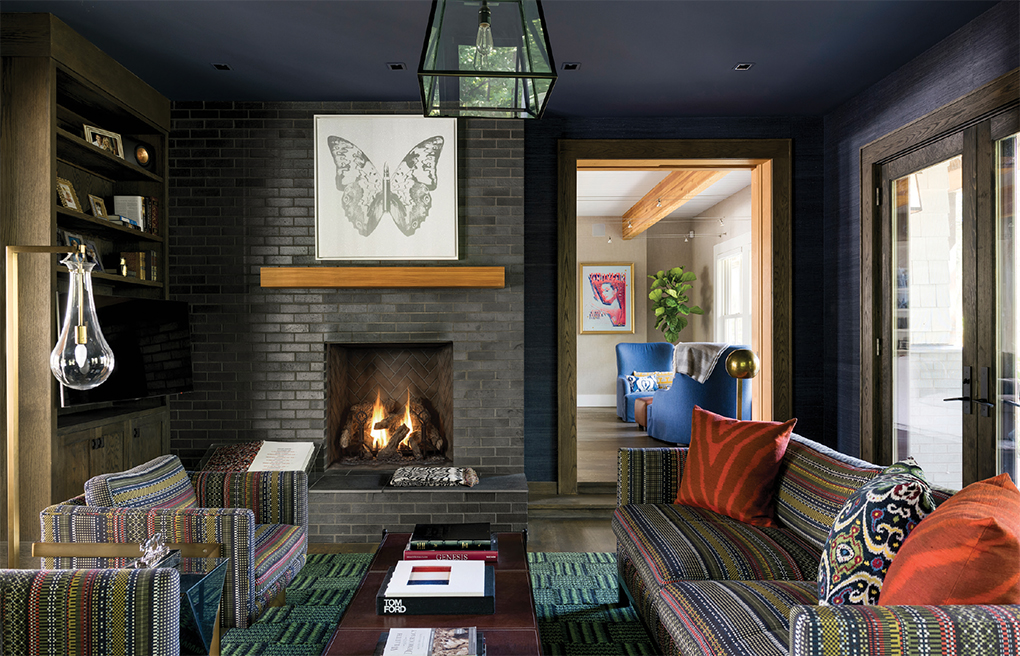A darkly colored den with brick fireplace, coffee table and seating.
