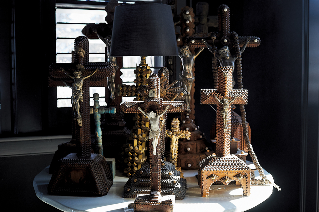 A table displaying a number of intricately carved crucifixes in Christine Ward's, the owner of Patina, home.