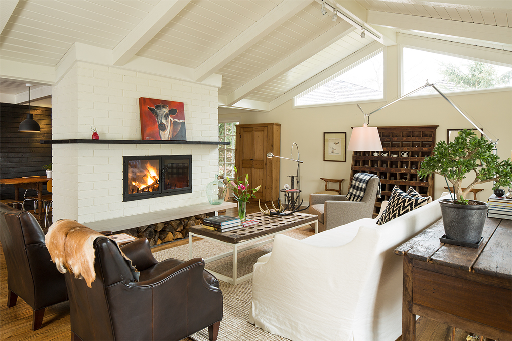 An open living room with seating surrounding a coffee table and lit fireplace.