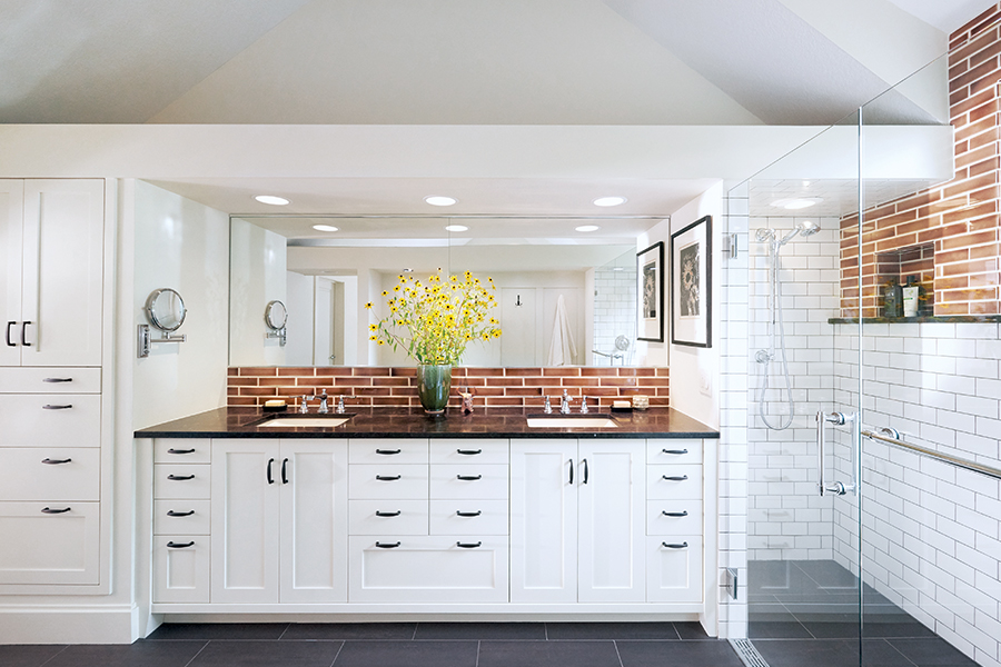 In a bathroom designed by Digiacomo Homes, flamed cohiba granite, polished chrome faucets, and bronze cabinet handles add contrast.