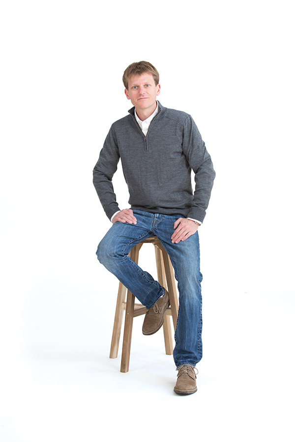 Photo of a man sitting on a wooden stool