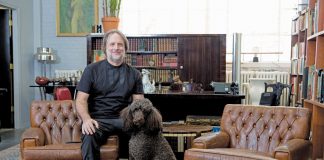 Peter Dyste sitting in a living room on a couch with his dog.