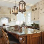 An Italian-styled kitchen shows off carved corbels, a heavily-veined granite, limestone hood hammered copper sink.