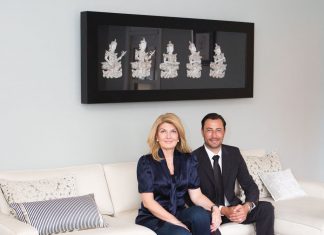 Daniel and Jane Green sit on a white sofa inside their home.