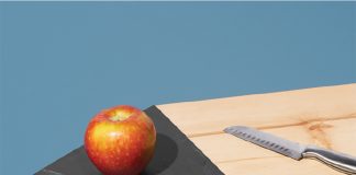 A cutting board by Tandem Made with an apple and knife resting on it.