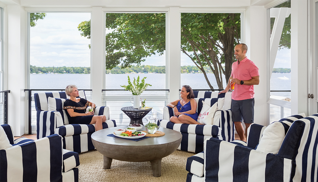 Three people relaxing in a screen porch on a lake.