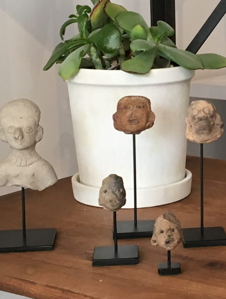 Heads on sticks in front of a plant at Historic Studio.