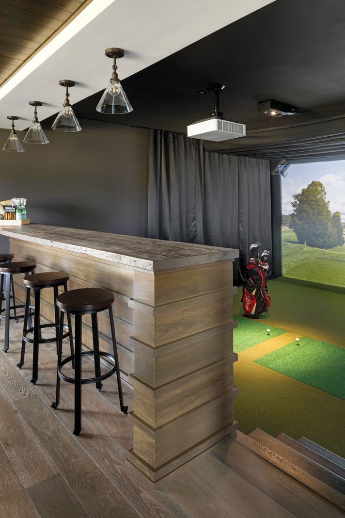 The golf simulator in the rambler’s lower level is the most unique aspect of the home–it can double as a video player, and nearby bar seating allows for spectator viewing. Part of Midwest Home's 2018 Luxury Home Tour.