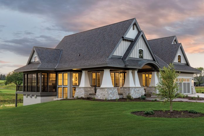 Stately tapered columns with wide stone foundations are a striking element in the exterior of this new modern cottage by Hartman Homes. Part of Midwest Home's 2018 Luxury Home Tour.