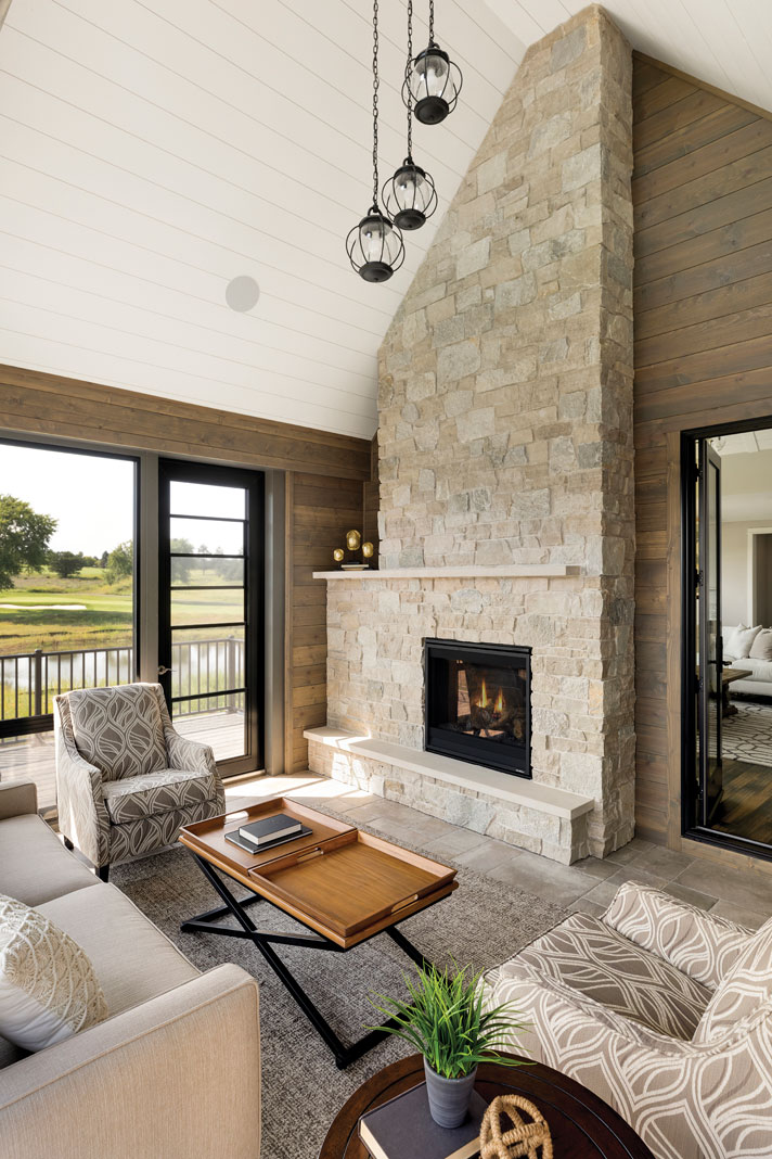 A three-season porch located off the home’s great room features the same vaulted ceiling in white shiplap detail and beautiful stone accents found in the main living area. Part of Midwest Home's 2018 Luxury Home Tour.