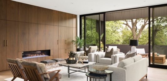 In the open plan living area, entertaining opportunities abound–guests can gather around the gas fireplace or jaunt out onto the balcony for a breath of fresh air. Part of Midwest Home's 2018 Luxury Home Tour.