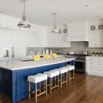 A wood floor kitchen with white cabinetry and a pop of blue paint on the island.