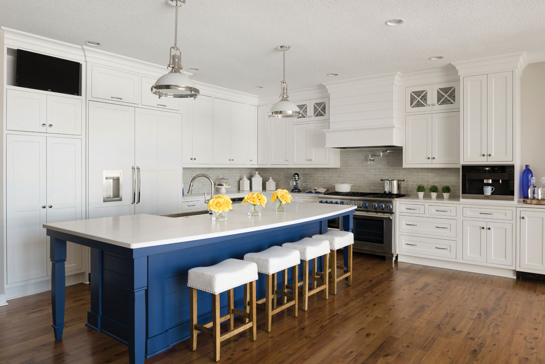 A wood floor kitchen with white cabinetry and a pop of blue paint on the island.