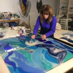 A woman creates artwork using colored glass